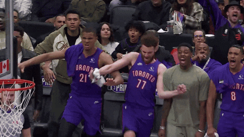 a group of toronto basketball players are playing a game in front of a crowd