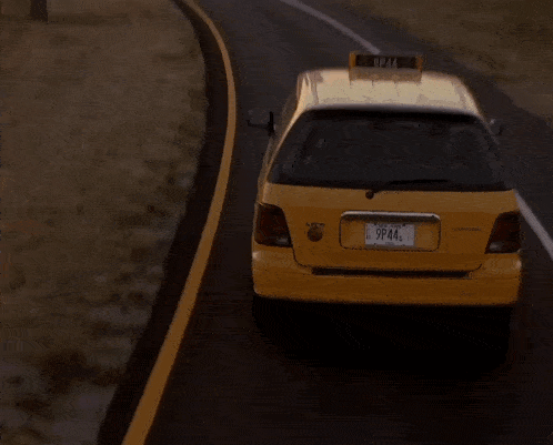 a taxi is driving down a road with a city in the background