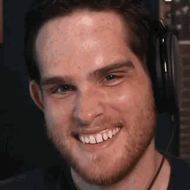 a man with a beard is wearing headphones and smiling for the camera