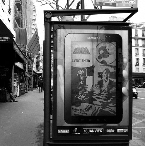 a black and white photo of a bus stop advertising a samsung tablet