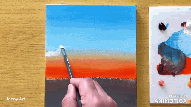 a person is painting a sunset with a brush