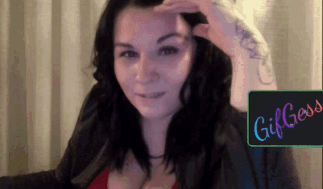 a woman with a tattoo on her arm stands in front of a sign that says gif gloss