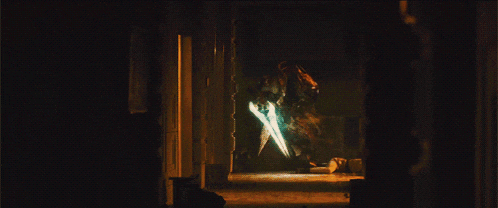 a person standing in a dark room with a light coming out of the door