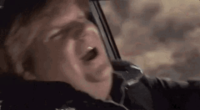 a man is yawning while sitting in a car with his mouth open .