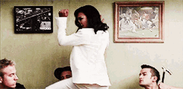 a woman in a white jacket is dancing in front of a group of men