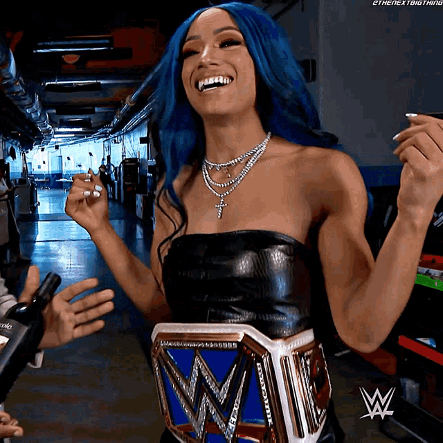 a woman with blue hair is wearing a wrestling belt with a w on it