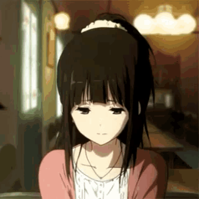 a girl with black hair and a ponytail is sitting at a table in a restaurant .