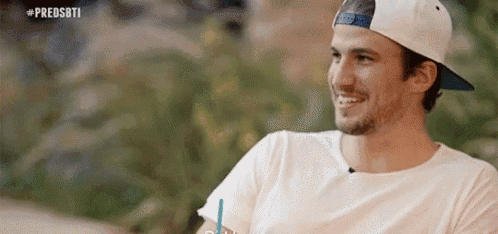 a man wearing a white hat and a white shirt is smiling while holding a drink .