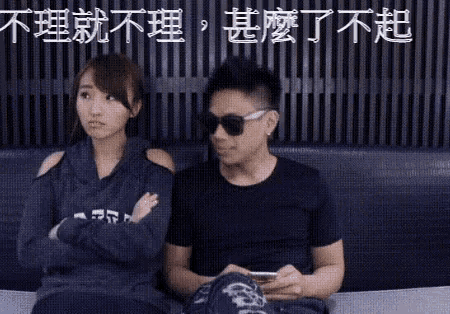 a man and a woman are sitting next to each other on a couch . the man is wearing sunglasses .