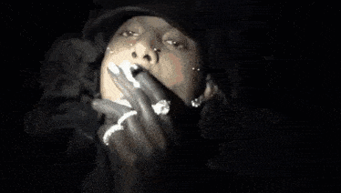 a close up of a person smoking a cigarette with smoke coming out of their mouth .