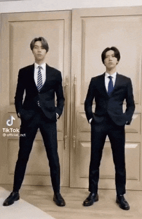 two men in suits are standing next to each other in front of a door .