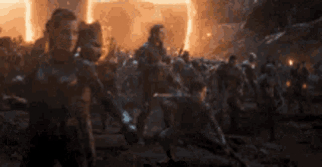 a group of people are standing in front of a fire in a movie .