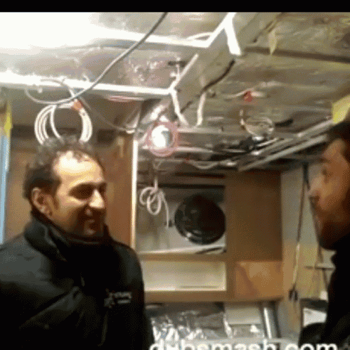 two men are talking in a room with the words dubmash.com on the bottom left