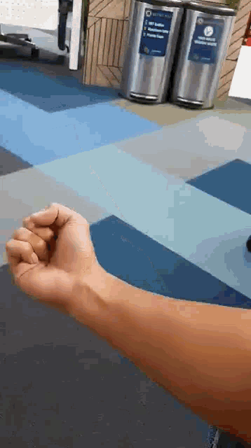 a person 's arm is shown in front of a trash can that says " recycle "