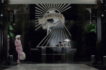 a woman in a pink suit and white hat stands in front of banner house