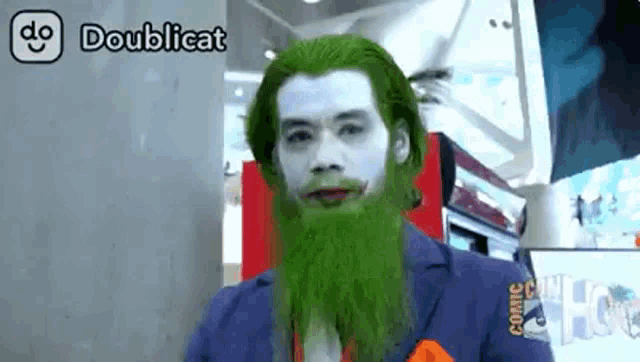 a man with a green beard and white paint on his face is wearing a doublecat costume