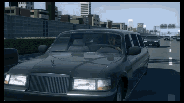 a man driving a limousine on a highway with a city in the background