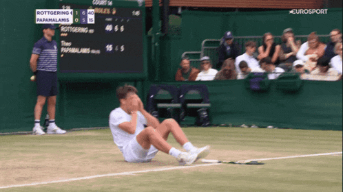 a tennis player is sitting on the court with a scoreboard behind him that says " eurosport "