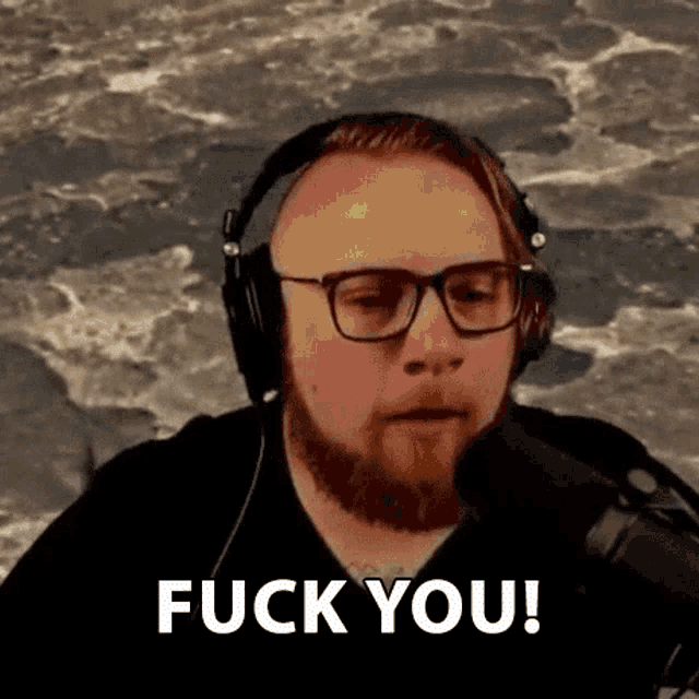 a man with a beard and headphones is talking into a microphone and saying `` fuck you '' .