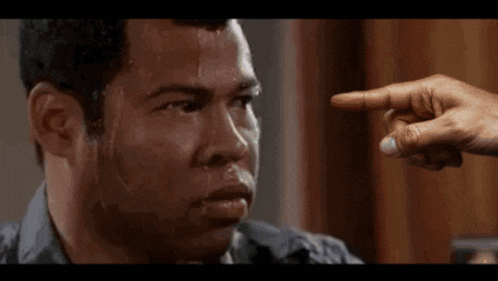 a man with sweat running down his face is being pointed at by another person 's hand .