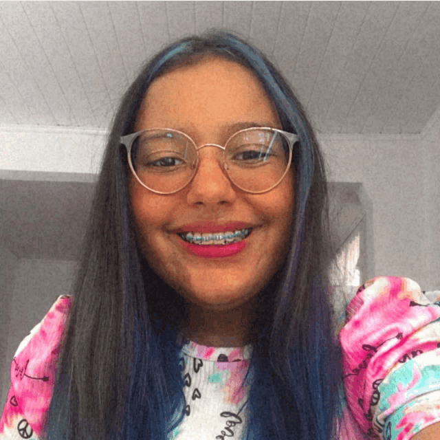 a girl with braces on her teeth wears glasses and a tie dye shirt