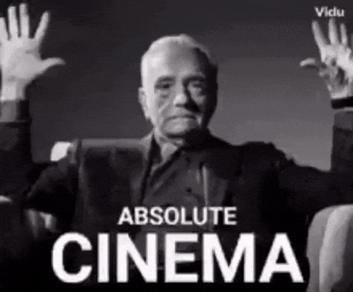 a man in a suit is sitting in a chair with his hands in the air and the words absolute cinema behind him