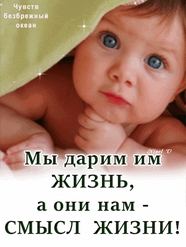 a baby with blue eyes is laying under a green blanket with foreign writing on it
