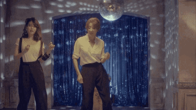 two women are dancing in a room with a disco ball behind them