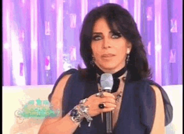 a woman in a blue dress is holding a microphone in her hand