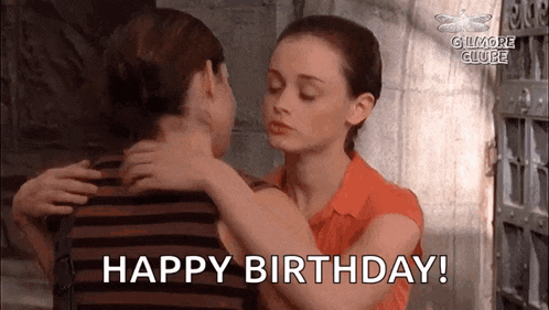 a woman is hugging another woman in a room and saying `` happy birthday '' .
