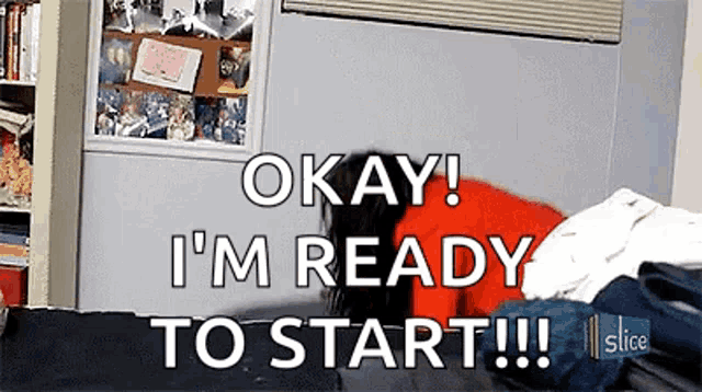a person is laying on a bed with a pile of clothes and says okay i 'm ready to start .