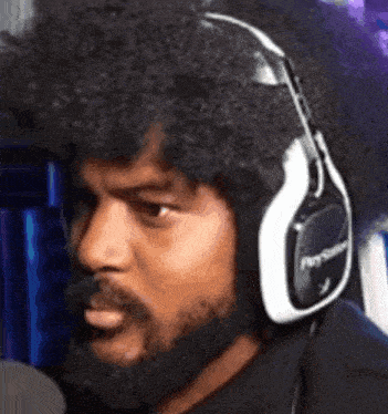 a man with a beard is wearing headphones and making a face .