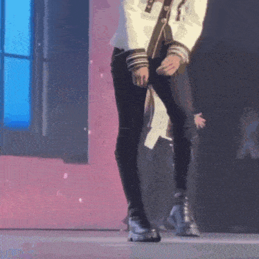 a man in a white jacket and black pants is standing on a stage .