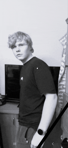 a young man standing in front of a television with a black ribbon around his neck