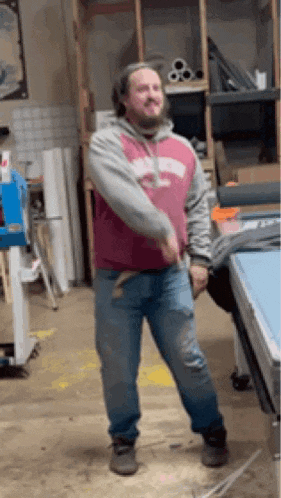 a man in a pink sweatshirt and jeans is dancing in a room