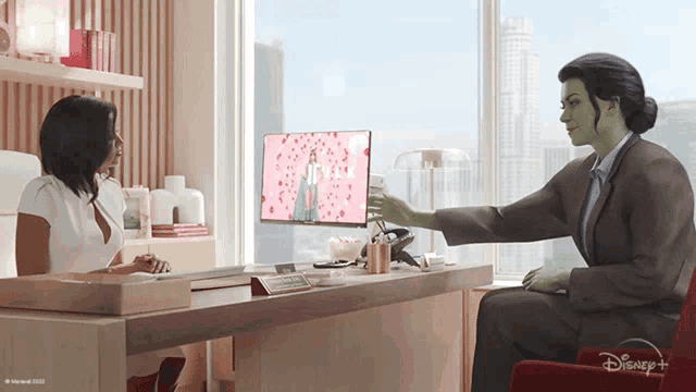 a woman is sitting at a desk with a disney logo on the bottom right