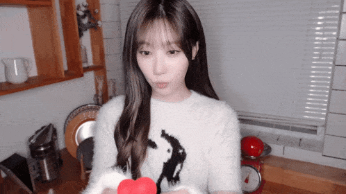 a girl in a white sweater holds a red heart