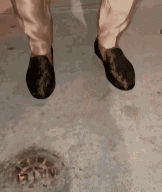 a person wearing white pants and black shoes is walking on a wet floor .