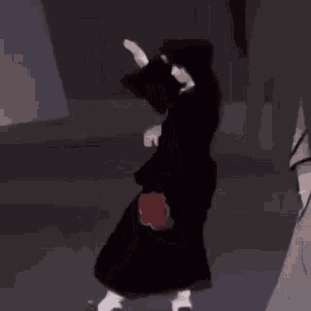 a cartoon character is dancing in a dark room while wearing a black robe .