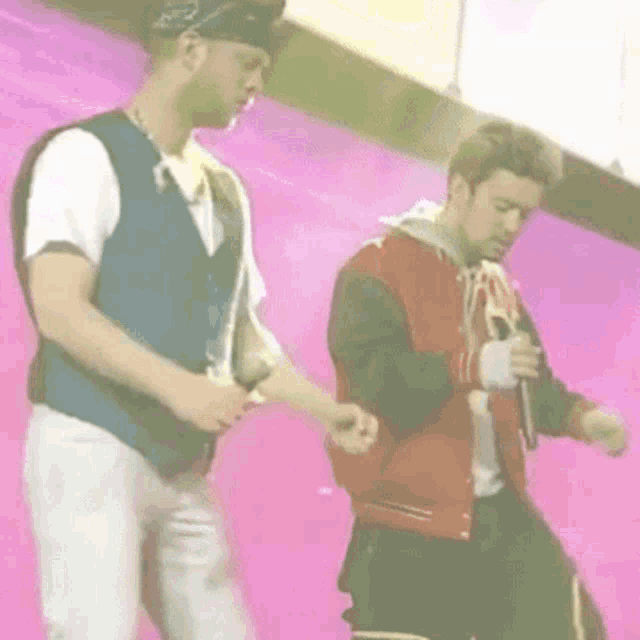 two men are standing on a stage holding hands and dancing .