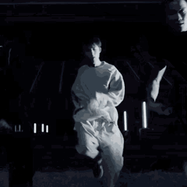 a man in a white shirt is walking through a field at night .