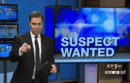 a man in a suit and tie stands in front of a suspect wanted sign