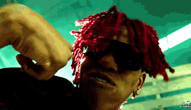 a man with red dreadlocks wearing sunglasses and a black shirt