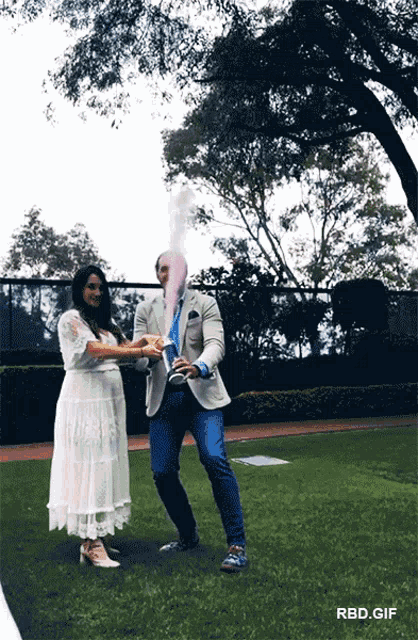 a man and a pregnant woman are holding hands while a man throws pink powder