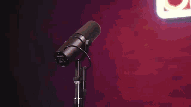 a young man in a hooded jacket is standing in front of a microphone .