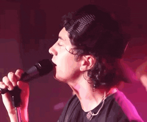a man singing into a microphone wearing a pink hat