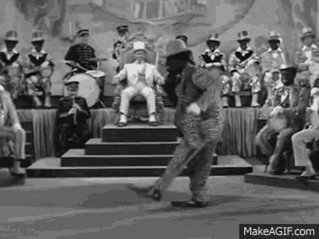 a black and white photo of a man sitting on a throne surrounded by a band .