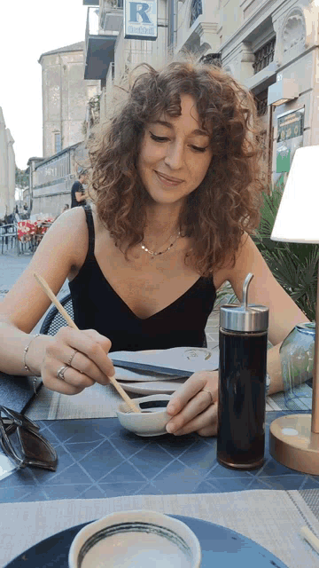 a woman sits at a table in front of a restaurant sign that says " ristorante "