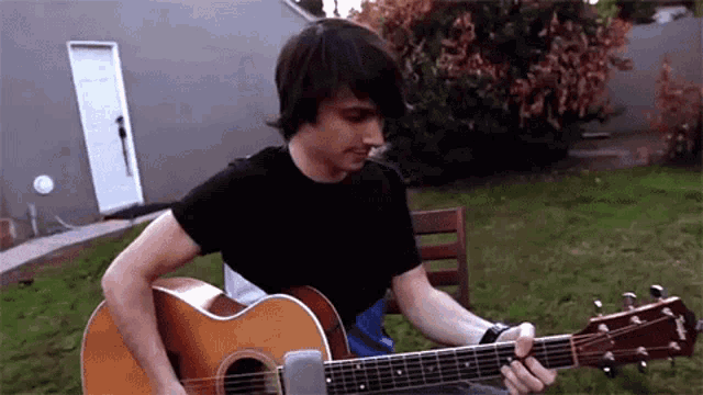 a man in a black shirt is playing a yamaha guitar
