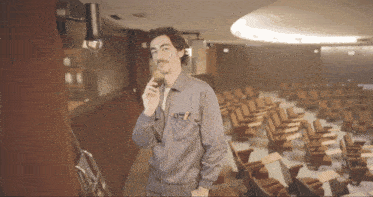 a man talking on a cell phone in an auditorium with empty seats